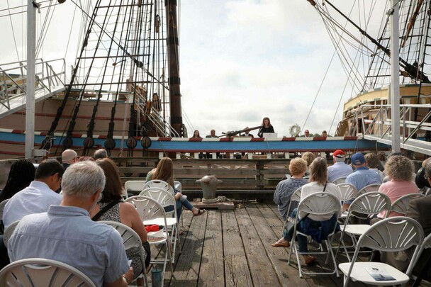 Seated guests enjoy remarks delivered from aboard Mayflower II.