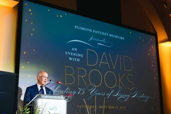 David Brooks stands at podium delivering keynote address.