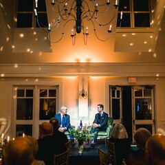 Jared Bowen and David Brooks in conversation in stage while event attendees dine.