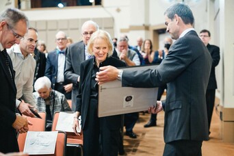 GBH's Jared Bowen hands Marty Mugar a framed Govenor's citation in front of gala guests.