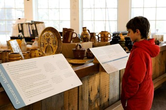 A young boy reads labels before a pottery exhibit in the Craft Center.