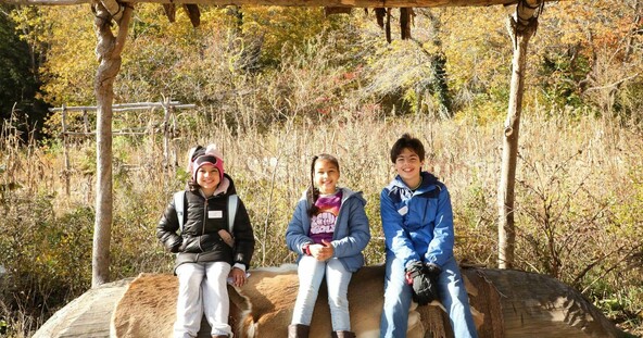 Smiling school children sit under an arbor at the Historic Patuxet Homesite.