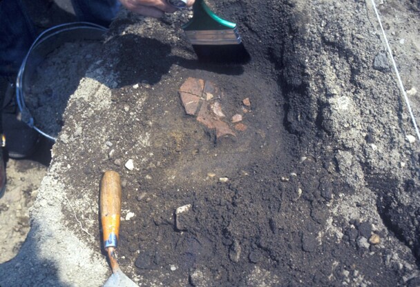 Archaeologists brush dirt from redware ceramic found at the Allerton-Cushman Site.