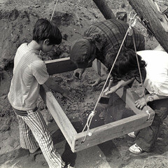 An archaeologist and two children look through fragments in a sieve on the Allerton-Cushman Site.