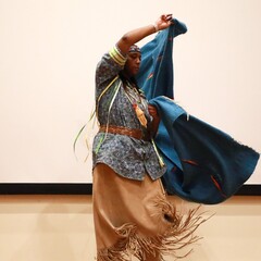A member of Standing Quiver Singers demonstrates the blanket dance on stage.