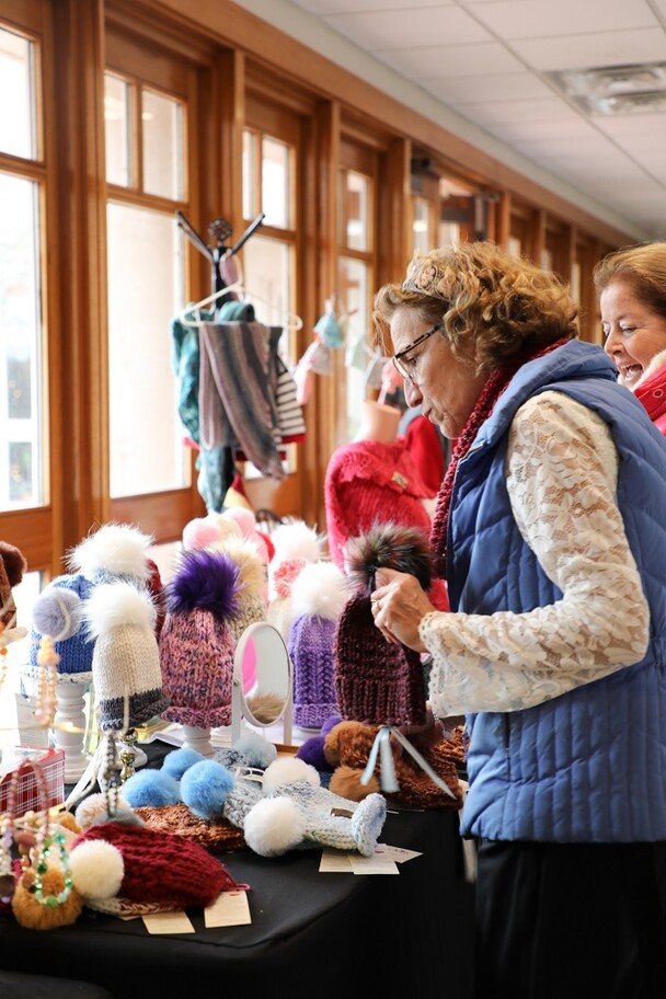 Women browse knitted hats at the Winter Fine Arts and Craft Fair.