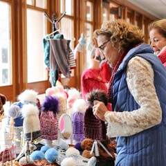 Women browse knitted hats at the Winter Fine Arts and Craft Fair.