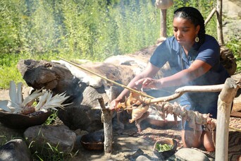Museum educator roasts quail over a fire at the Historic Patuxet Homesite.