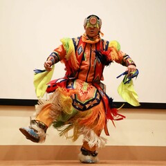 Dancer with Standing Quiver demonstrates a dance in fancy dress regalia.