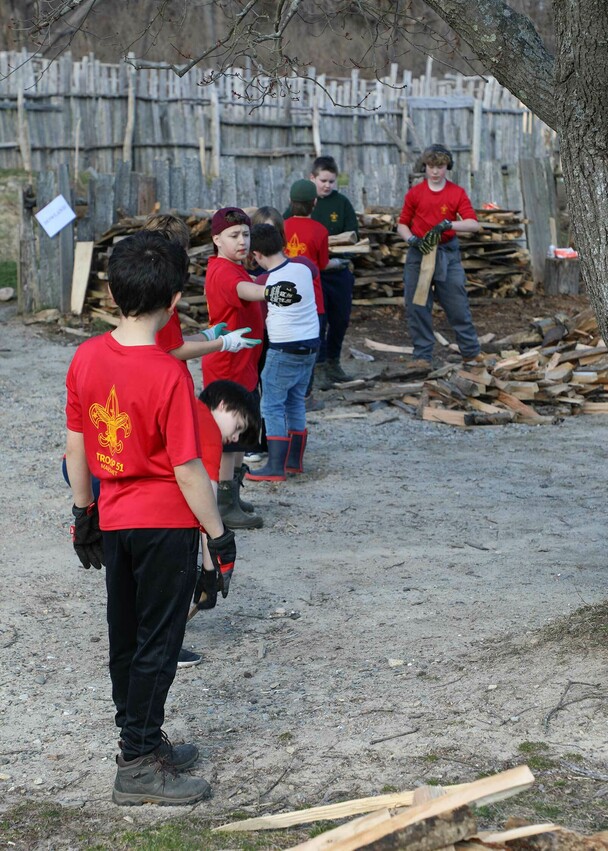 Young colunteers stacking wood line village clean up day