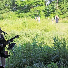 Female musician plays the guitar and sings at Plimoth Patuxet.