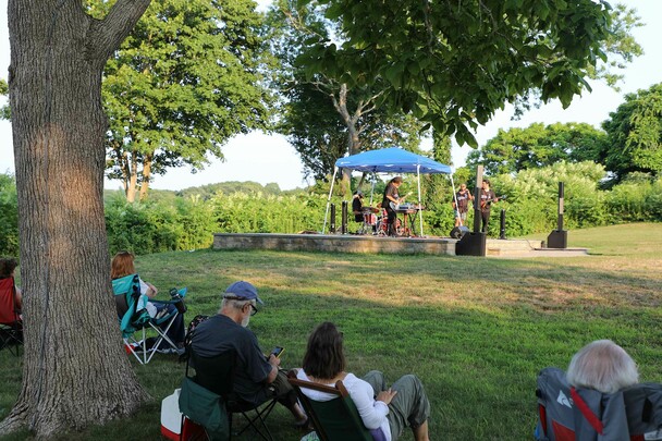 Guests sitting tree shade the groovalottos perform eel river stage