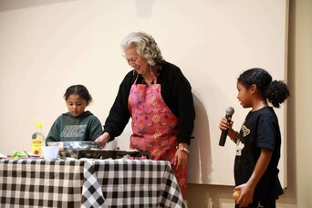 Sherry Pocknett leads a cooking demonstration on stage with her two grandchildren.