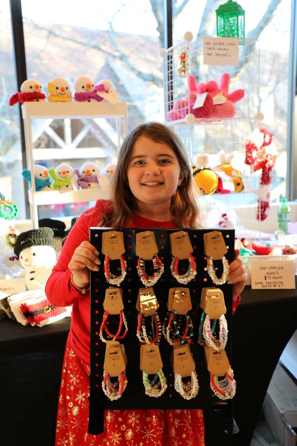 A crafter holds up a display of friendship bracelets that she has made.