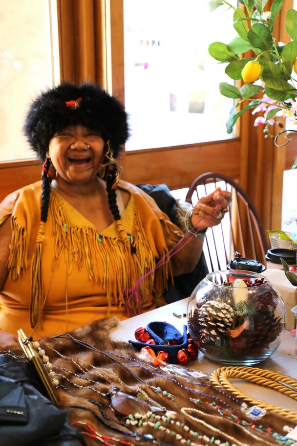 Indigenous Artisan Fellow sits at a table displaying her art and craft.