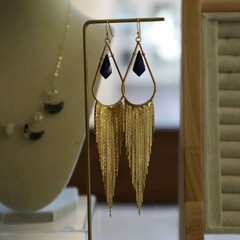 Dangle earrings displayed on a table with additional pieces of jewelry.