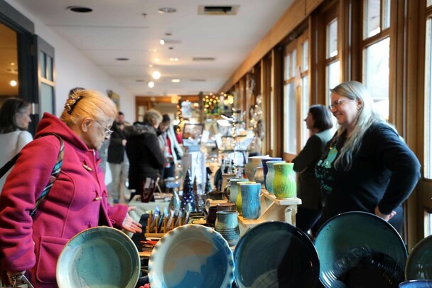 Winter Fair guest peruses table display of pottery.