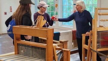 Volunteer hands wool sample to Museum guest.