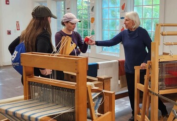 Volunteer hands wool sample to Museum guest.