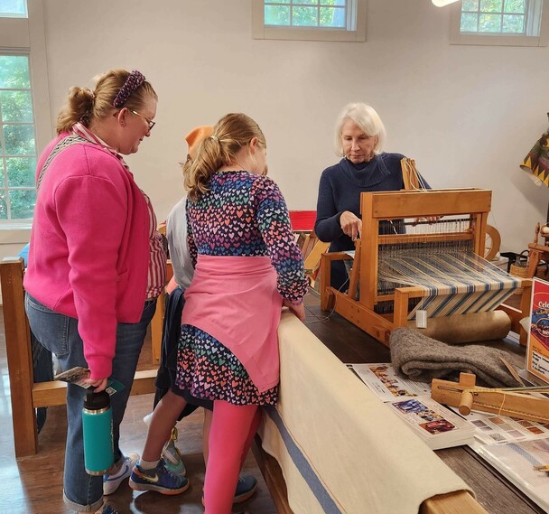 Guests watch a volunteer process wool.