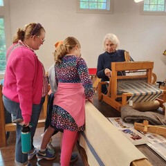 Guests watch a volunteer process wool.