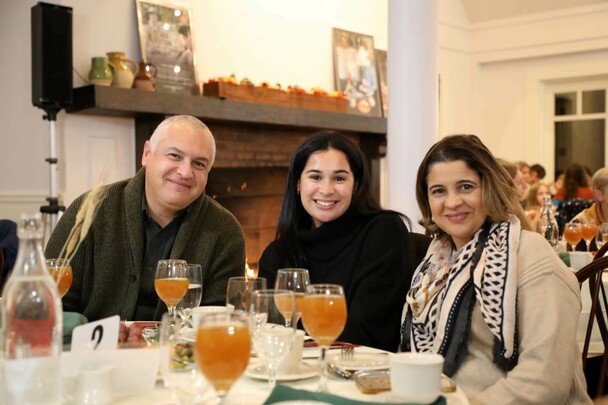 Three guests seated at Thanksgiving table with glasses of apple cider