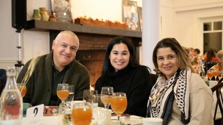 Three guests seated at Thanksgiving table with glasses of apple cider