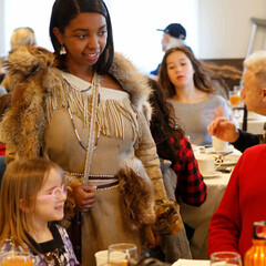 Indigenous Educator in Wampanoag regalia greets Thanksgiving guests