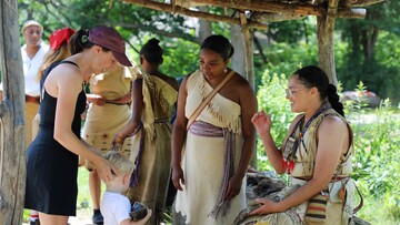 Mother and child guest engage with Educators at the Shade Arbor on the Historic Patuxet Homesite