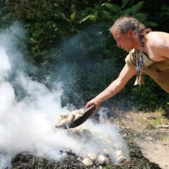 Indigenous Educator tosses bowl of quahogs onto burning clambake