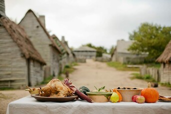 Table set for Thanksgiving in the English village with pilgrim houses in the background.