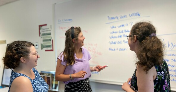 Three teachers talk around whiteboard