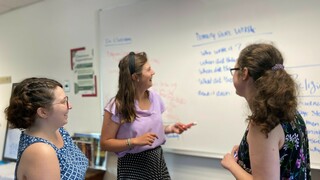 Three teachers talk around whiteboard