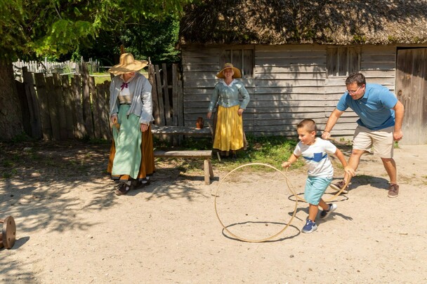 Father and son spin hoops with Pilgrims in English Village