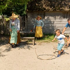 Father and son spin hoops with Pilgrims in English Village