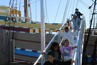 Children on a field-trip descend the ramp from the decks of Mayflower II.