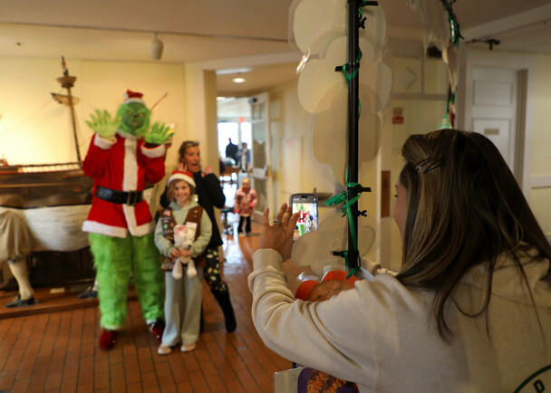 A mother snaps a photo of her daughters posed with the Grinch before the Moo-flower.