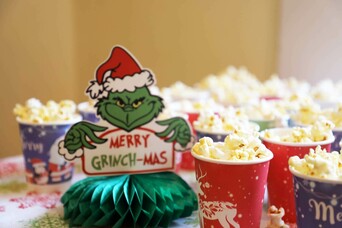 Festive cups of popcorn surround a Grinch holiday table decoration.
