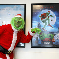 The Grinch poses with his own framed movie poster.