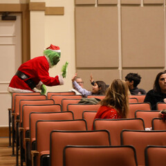 The Grinch high-fives children seated in a movie theater.
