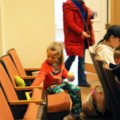 Child in pajamas sets a stuffed animals of the Grinch into a movie theater seat.