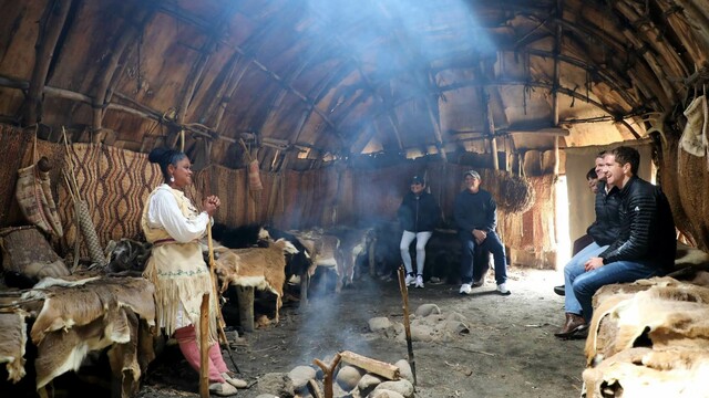 Museum Educator speaks with seated guests in a wetu on the Historic Patuxet Homesite