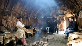 Museum Educator speaks with seated guests in a wetu on the Historic Patuxet Homesite