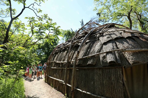 Guests line up to enter the bark covered wetu on the Historic Patuxet Homesite in summer.