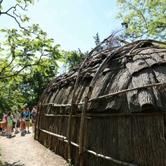 Guests line up to enter the bark covered wetu on the Historic Patuxet Homesite in summer.