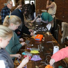 Crowded craft table in the Craft center with participants of all ages.