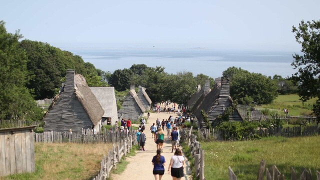 A group of visitors walk down the main path of the 17th-Century English Village