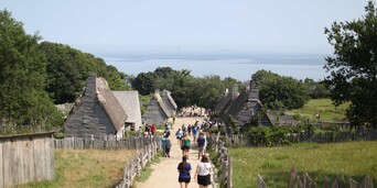 A group of visitors walk down the main path of the 17th-Century English Village