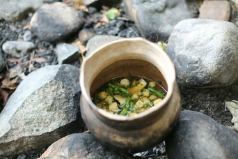 Clay cooking pot with stew cooks in outdoor setting