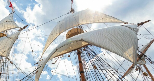 Mayflower white sails blow in the wind against a blue sky